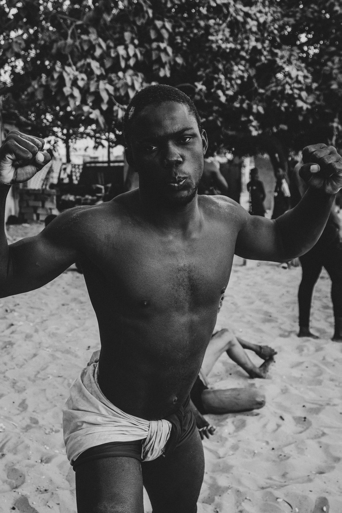 A wrestler raising both fists under the trees