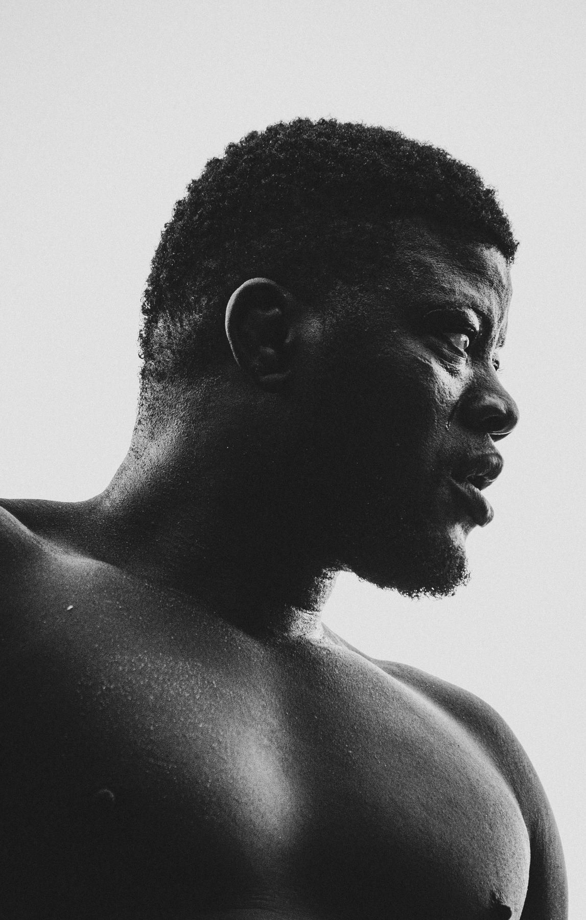 Backlit profile portrait of a wrestler against a pale sky